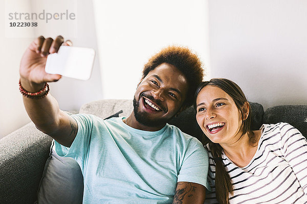 Glückliches junges Paar fotografiert sich selbst mit dem Smartphone