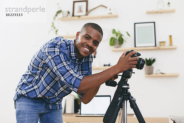 Porträt eines lächelnden jungen Mannes bei der Arbeit in seinem Fotostudio