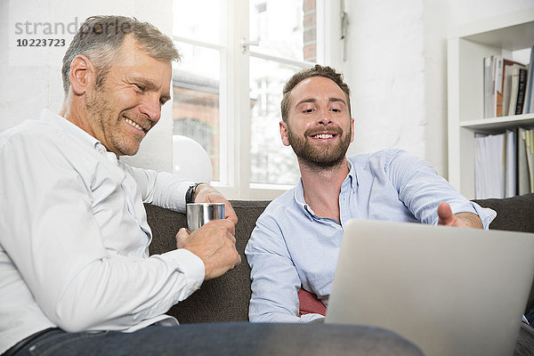 Zwei lächelnde Geschäftsleute teilen sich einen Laptop