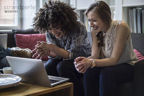 Zwei glückliche junge Frauen teilen sich einen Laptop