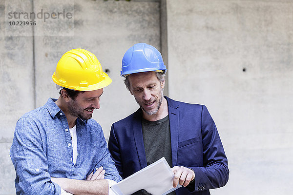 Zwei Männer auf der Baustelle betrachten Dokument