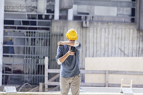 Mann mit Handy mit Schutzhelm auf der Baustelle
