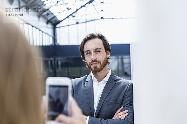 Geschäftsfrau beim Fotografieren ihres Kollegen mit dem Smartphone