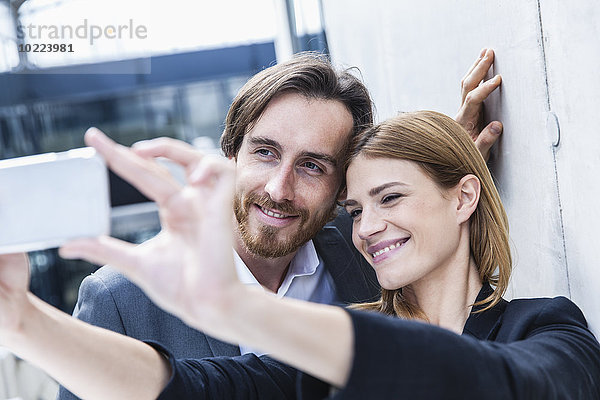 Porträt von zwei Geschäftsleuten  die einen Selfie mit Smartphone nehmen