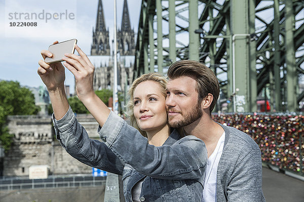 Deutschland  Köln  junges Pärchen mit Smartphone auf der Hohenzollernbrücke