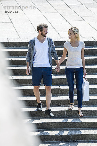 Deutschland  Köln  glückliches junges Paar  das die Treppe hinuntergeht