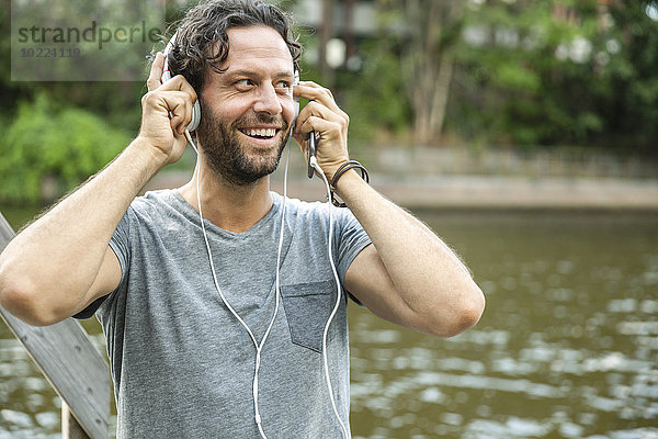 Glücklicher Mann beim Musikhören am Wasser