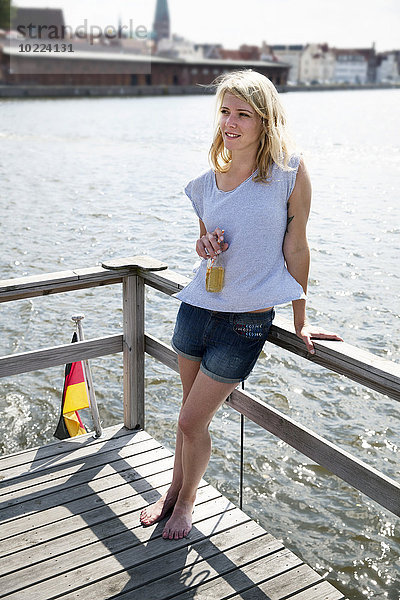 Lächelnde junge Frau mit Bierflasche auf einem Hausboot