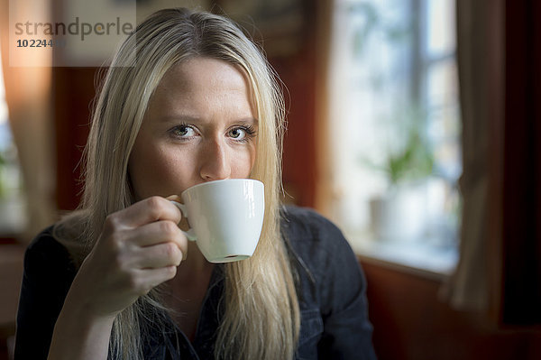 Porträt einer blonden Frau beim Kaffeetrinken