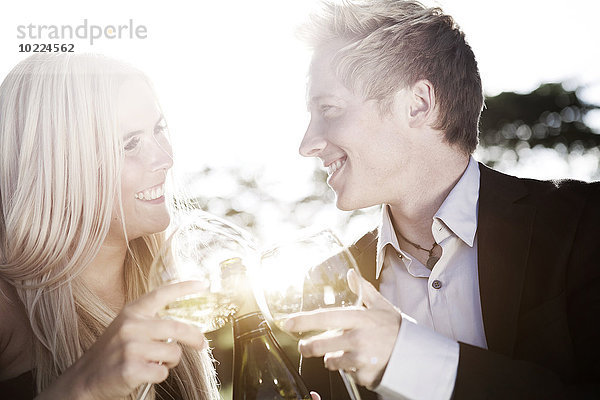 Fröhliches junges Paar im Freien beim Weintrinken