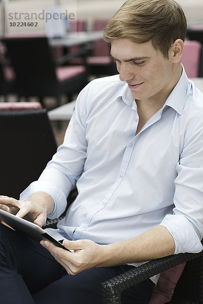 Junger Mann sitzt im Coffee-Shop mit digitalem Laptop