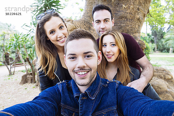 Vier Freunde  die einen Selfie in einem Park nehmen