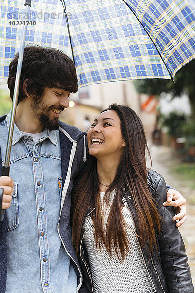 Glückliches junges Paar mit Regenschirm