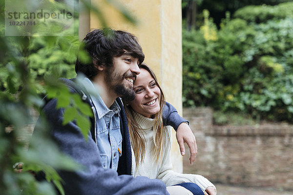 Ein glückliches junges Paar sitzt Arm in Arm und ruht sich aus.