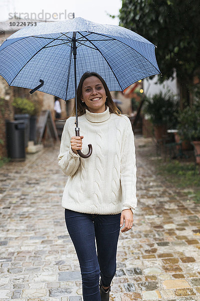 Italien  San Gimignano  Porträt einer lächelnden jungen Frau mit Regenschirm