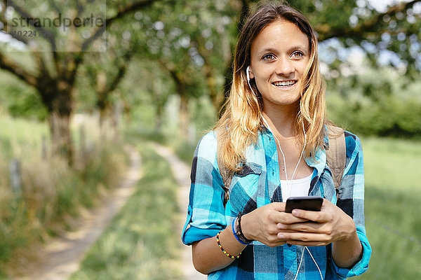 Porträt eines lächelnden Mädchens mit Smartphone und Kopfhörer