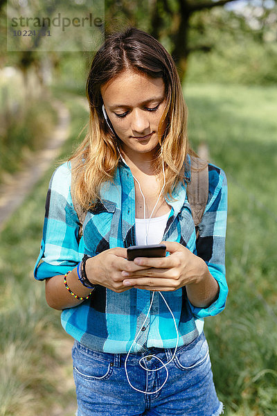 Teenagerin mit Smartphone und Kopfhörer