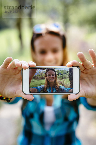 Lächelndes Teenagermädchen nimmt einen Selfie mit Smartphone