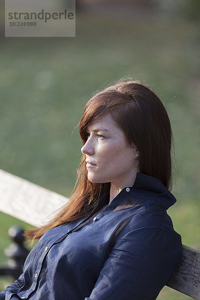 Porträt einer Frau auf einer Parkbank sitzend