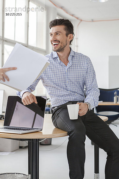 Porträt eines lächelnden Geschäftsmannes mit Kaffeetasse im Büro