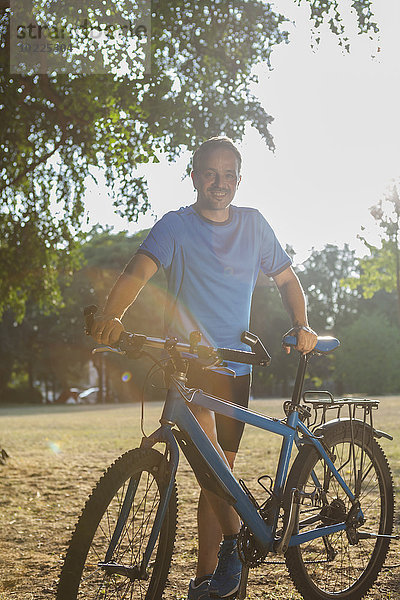 Porträt eines lächelnden Mannes im Park mit Fahrrad