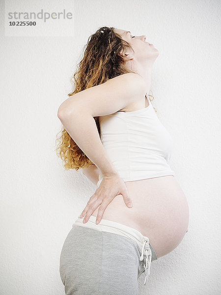 Eine schwangere Frau hält sich zurück.