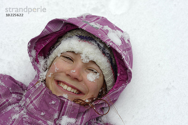Porträt eines lächelnden Mädchens auf Schnee liegend