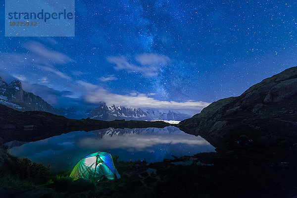 Frankreich  Mont Blanc  Lake Cheserys  beleuchtetes Zelt am Ufer des Sees bei Nacht mit Milchstraße und Mount Blanc im See reflektiert