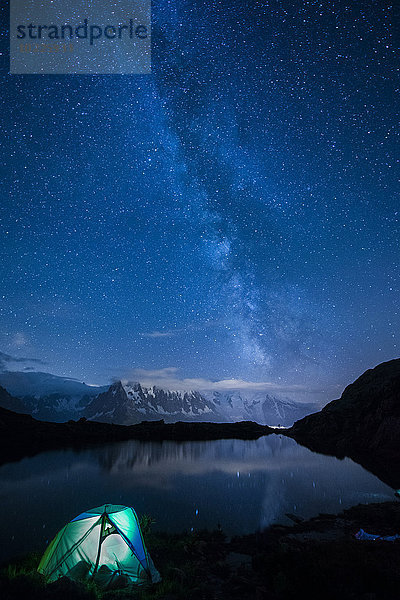 Frankreich  Mont Blanc  Lake Cheserys  beleuchtetes Zelt am Ufer des Sees bei Nacht mit Milchstraße und Mount Blanc im See reflektiert