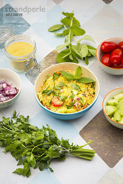 Schale mit zubereitetem Couscous-Salat und Zutaten
