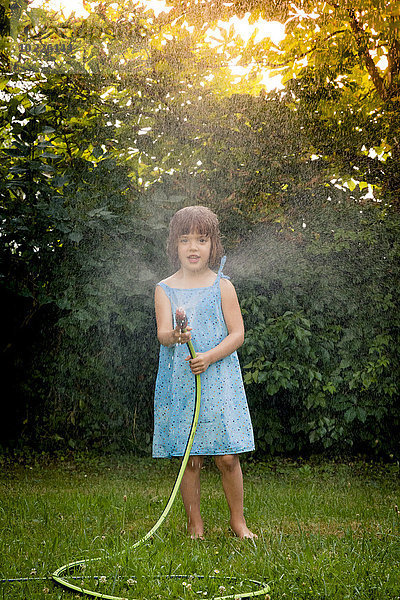 Kleines Mädchen mit Gartenschlauch