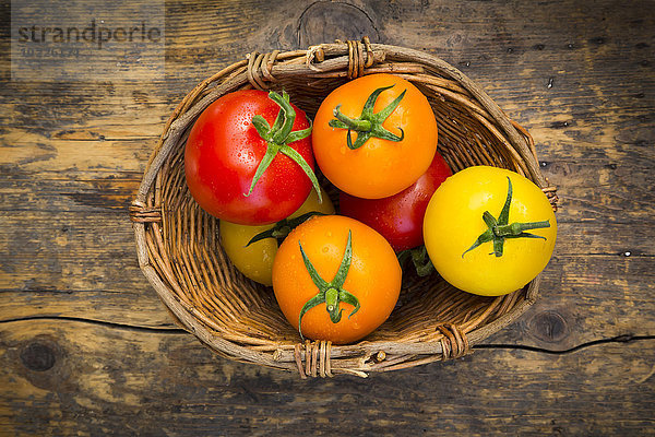 Weidenkorb mit verschiedenen Tomaten auf Holz