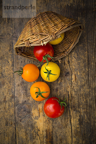 Wickerbasket und verschiedene Tomaten auf Holz