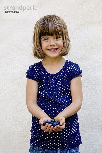 Porträt eines kleinen Mädchens mit zwei Handvoll Blaubeeren