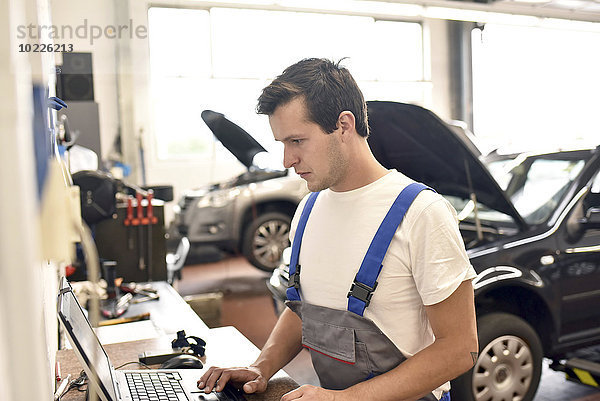 Automechaniker mit Laptop in der Garage