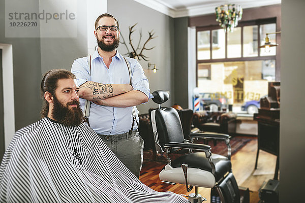 Porträt eines lächelnden Friseurs mit Kunden im Friseursalon