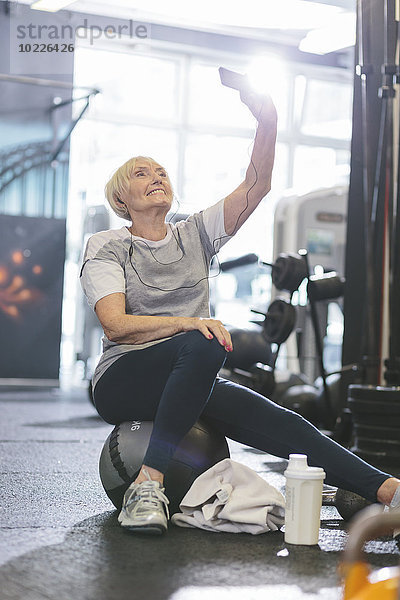 Seniorenfrau im Fitnessstudio mit einem Selfie