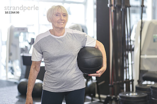 Seniorin in der Turnhalle mit Medizinball