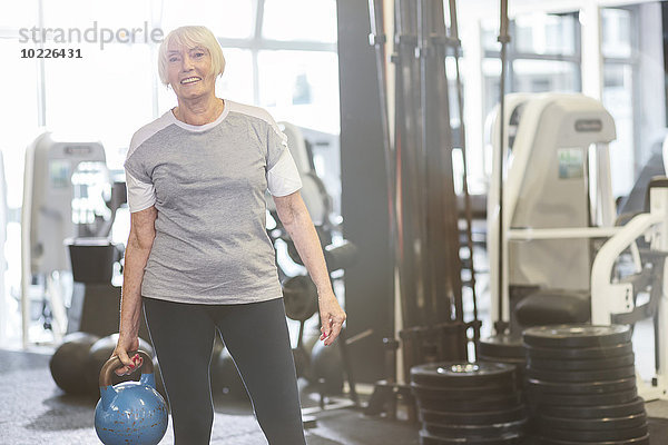 Seniorenfrau in der Turnhalle mit Kettlebell