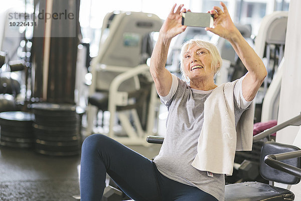 Seniorenfrau im Fitnessstudio mit einem Selfie