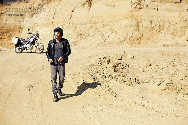 Erwachsener Mann mit Motorrad im Sandkasten