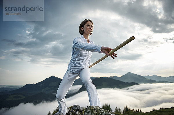 Österreich  Kranzhorn  Mittlere erwachsene Frau beim Stockkampf auf dem Berggipfel