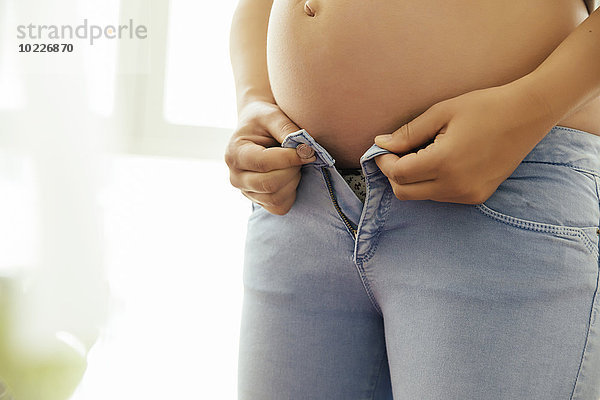 Schwangere Frau versucht  ihre Jeans zu knöpfen  Nahaufnahme