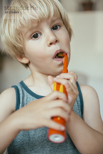 Porträt eines kleinen Jungen  der seine Zähne mit einer elektrischen Zahnbürste putzt.