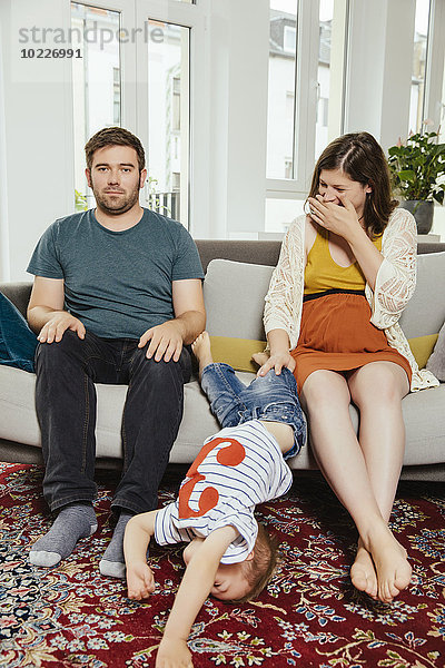 Gestörtes Familienporträt auf einem Sofa zu Hause mit wegspringendem Sohn