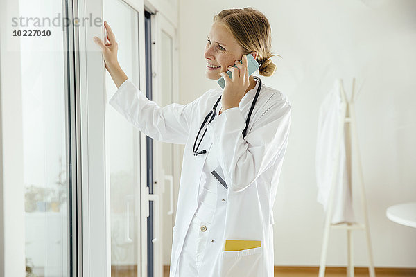 Lächelnde Ärztin im Gespräch mit dem Handy