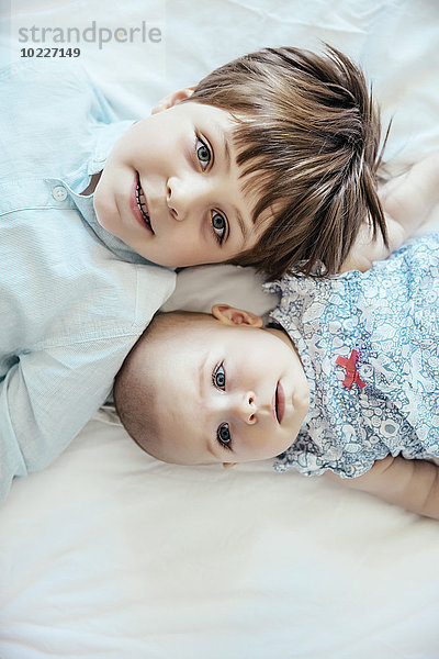 Mädchen und Bruder auf dem Bett liegend