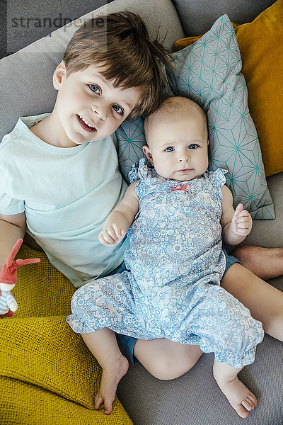 Baby Mädchen und Bruder kuscheln auf der Couch