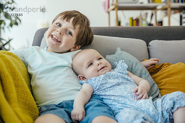 Lächelndes Mädchen und Bruder auf der Couch