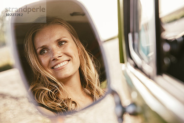 Gesicht der lächelnden Frau im Außenspiegel des Lieferwagens reflektiert